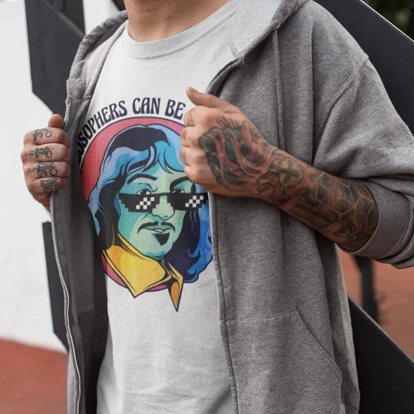 "Hombre tatuado vistiendo una playera de color blanco con diseno de filosofo psicodelico, tonos rojo, azul y amarillo"